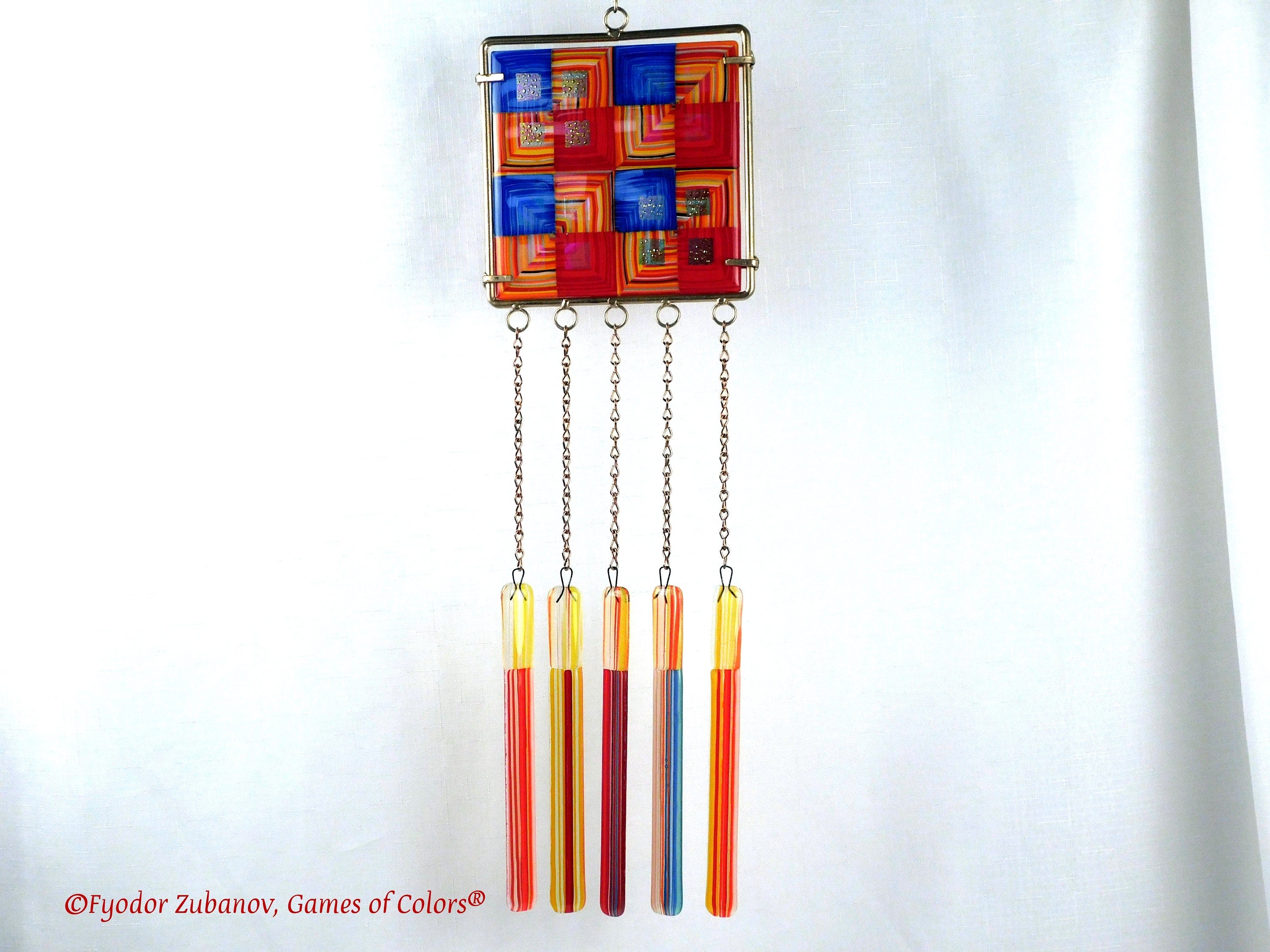 Wind chime with the main glass body surrounded by black frame and glass strips hanging on short chains