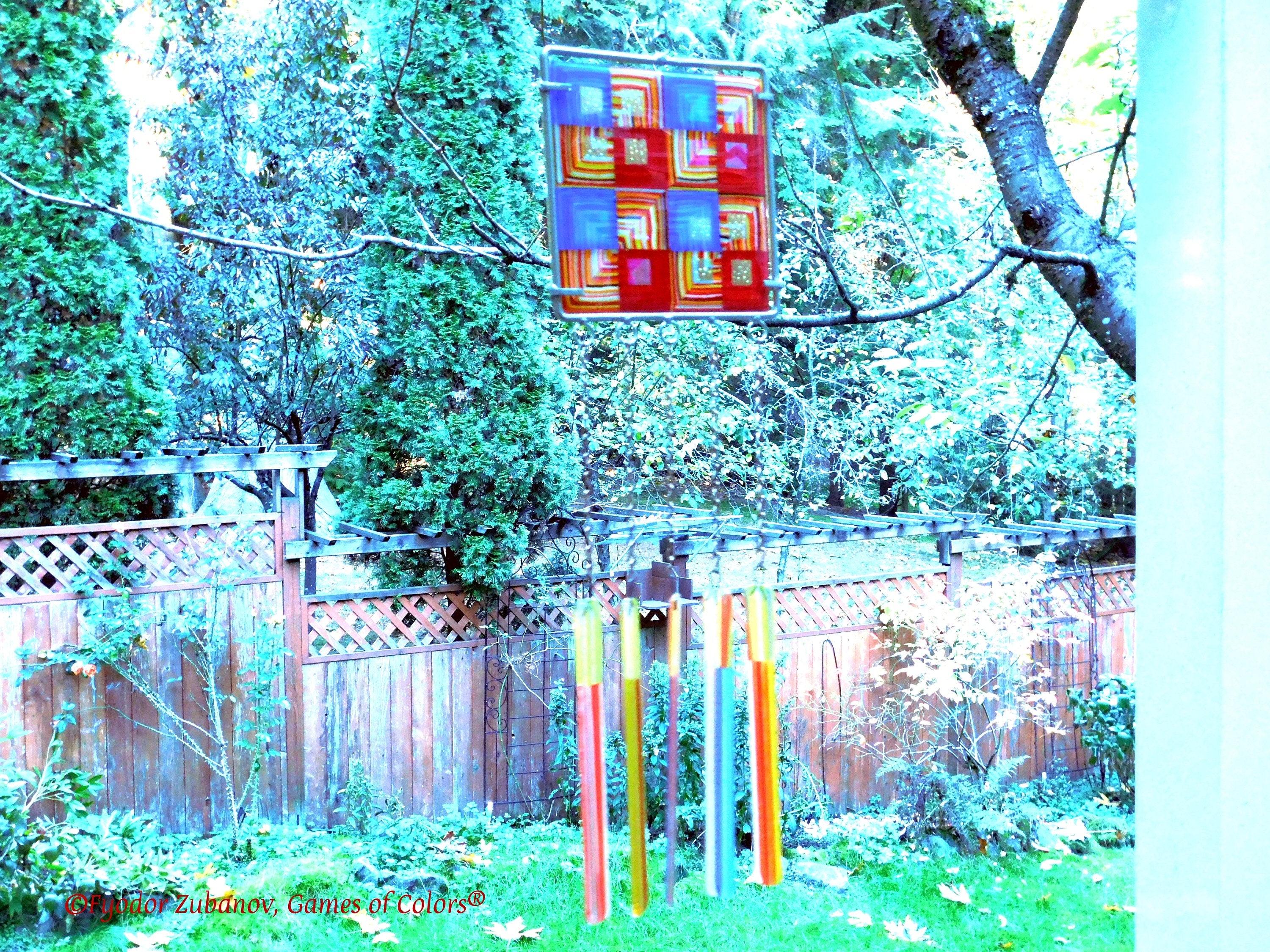 Wind chime with the main glass body surrounded by black frame and glass strips hanging on short chains