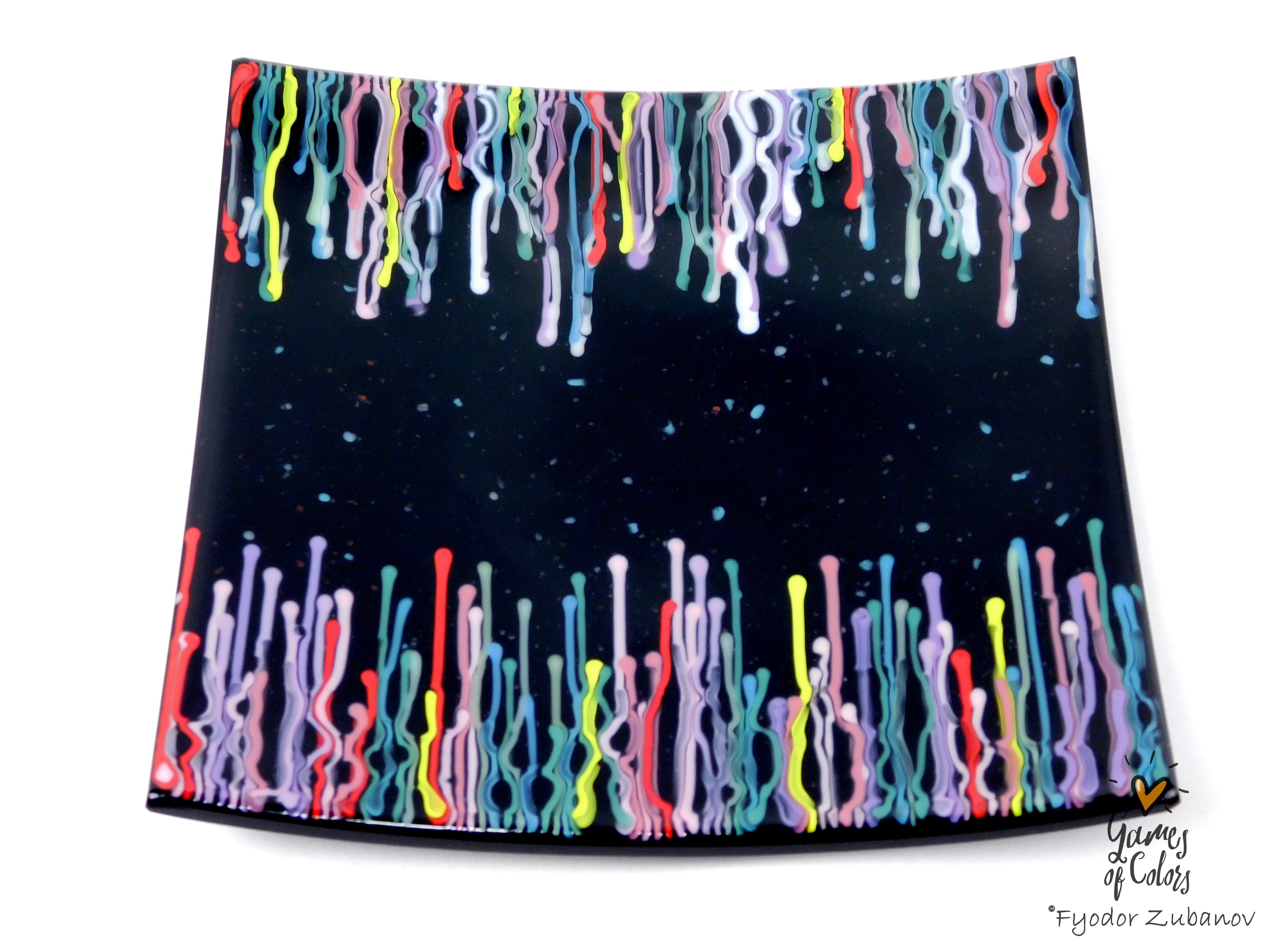 A black square glass plate featuring a colorful dripping paint pattern along the top and bottom edges, shown on a plain white background with a small artist signature in the lower right corner.