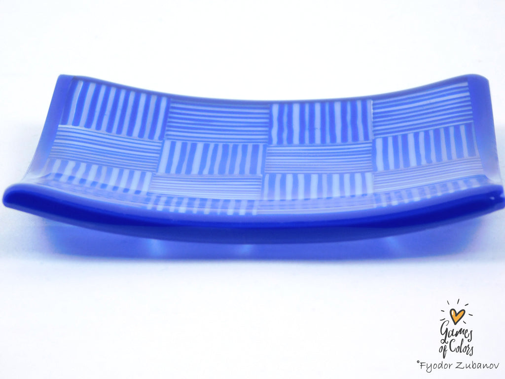 A curved cobalt blue glass plate with a woven basketweave pattern created by alternating thick and thin stripes, shown on a white background.