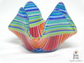 A colorful fused glass candle holder with a mountain-like flared rim, featuring horizontal striped patterns in blue, green, orange, red, and white on a white background.