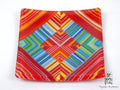 A square glass plate featuring a vibrant, symmetrical geometric pattern with stripes of red, orange, yellow, green, blue, and purple on a white background.