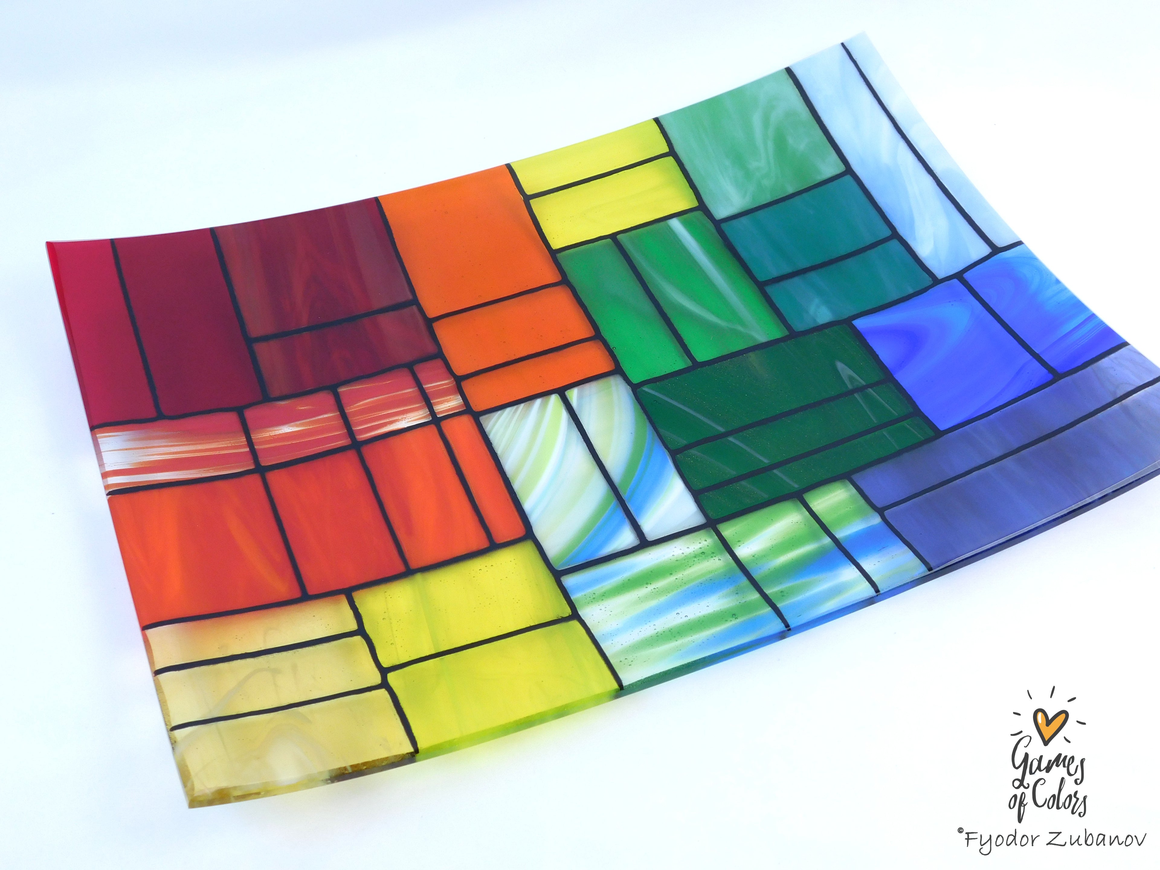 A colorful stained-glass-style rectangular plate or tray with a mosaic of multiple colors glass sections separated by dark grout lines, photographed on a white background. The plate is from the Gentle Color Mix collection. Branded as Fyodor Zubanov, Games of Colors
