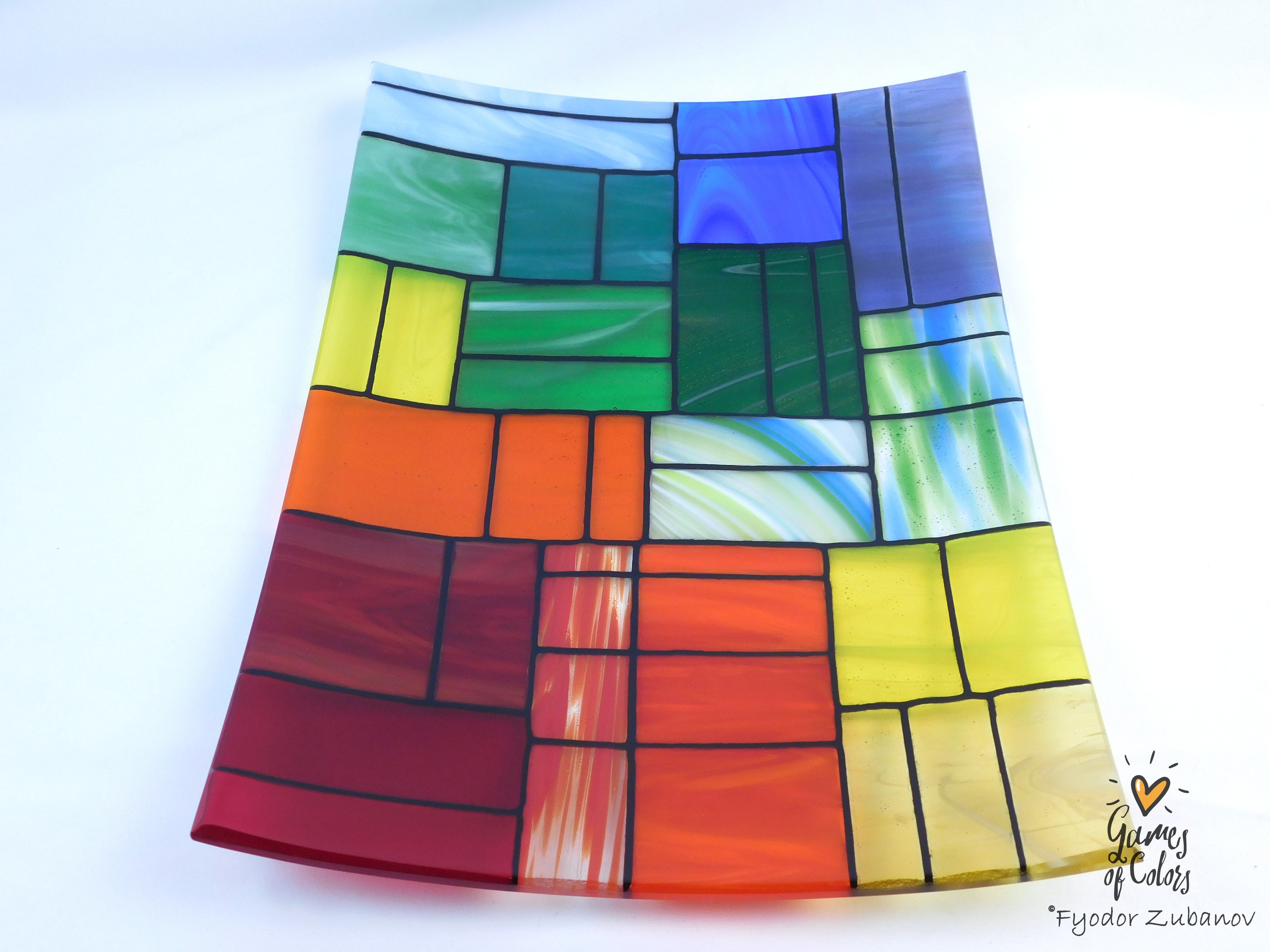 A colorful stained-glass-style rectangular plate or tray with a mosaic of multiple colors glass sections separated by dark grout lines, photographed on a white background. The plate is from the Gentle Color Mix collection. Branded as Fyodor Zubanov, Games of Colors