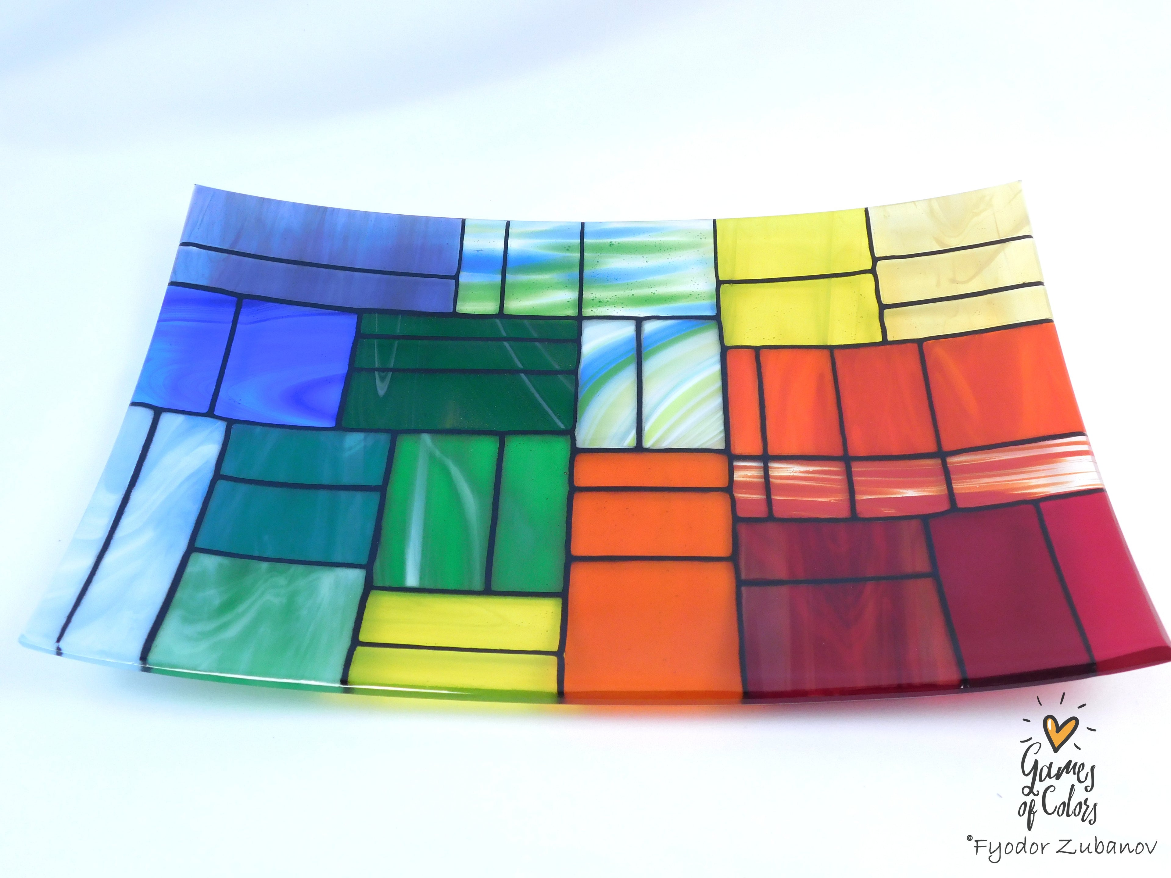 A colorful stained-glass-style rectangular plate or tray with a mosaic of multiple colors glass sections separated by dark grout lines, photographed on a white background. The plate is from the Gentle Color Mix collection. Branded as Fyodor Zubanov, Games of Colors