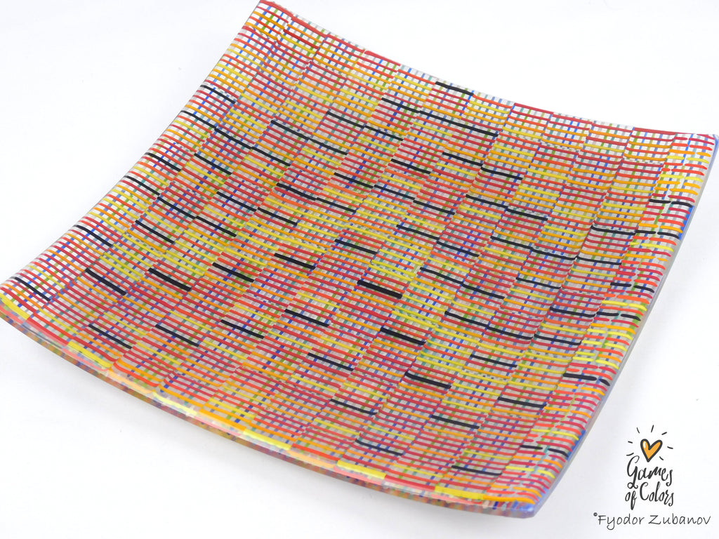 A square glass plate imitating fabric with a vibrant, multicolored geometric pattern featuring diagonal stripes and mesh-like textures in yellow, blue, green. and a watermark in the bottom right corner reads 'Fyodor Zubanov' and 'Games of Colors'.