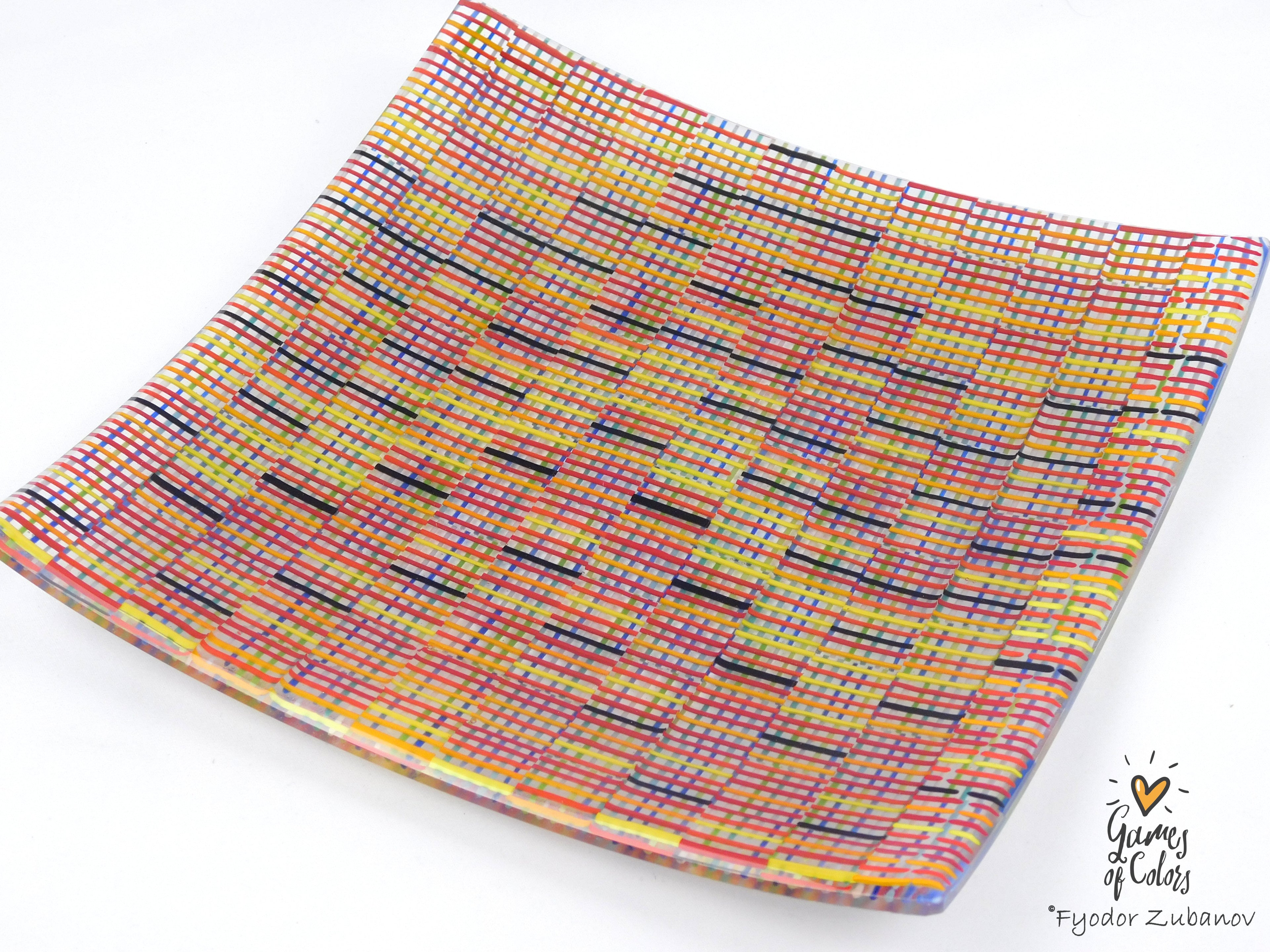 A square glass plate imitating fabric with a vibrant, multicolored geometric pattern featuring diagonal stripes and mesh-like textures in yellow, blue, green. and a watermark in the bottom right corner reads 'Fyodor Zubanov' and 'Games of Colors'.