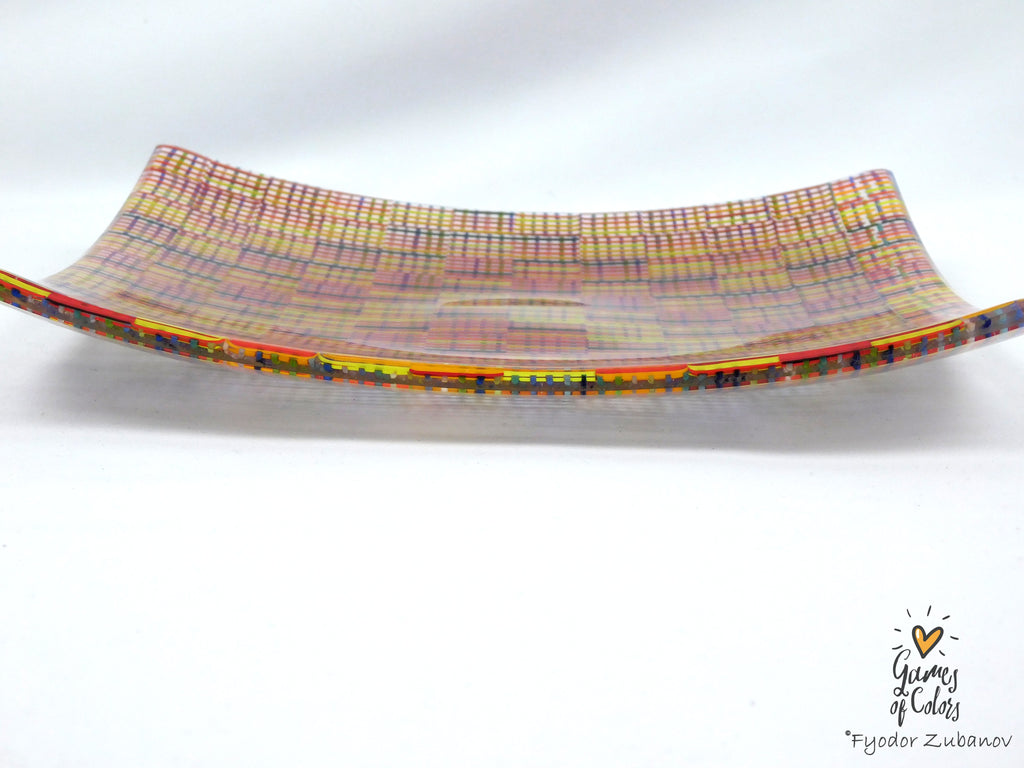 A square glass plate imitating fabric with a vibrant, multicolored geometric pattern featuring diagonal stripes and mesh-like textures in yellow, blue, green. and a watermark in the bottom right corner reads 'Fyodor Zubanov' and 'Games of Colors'.