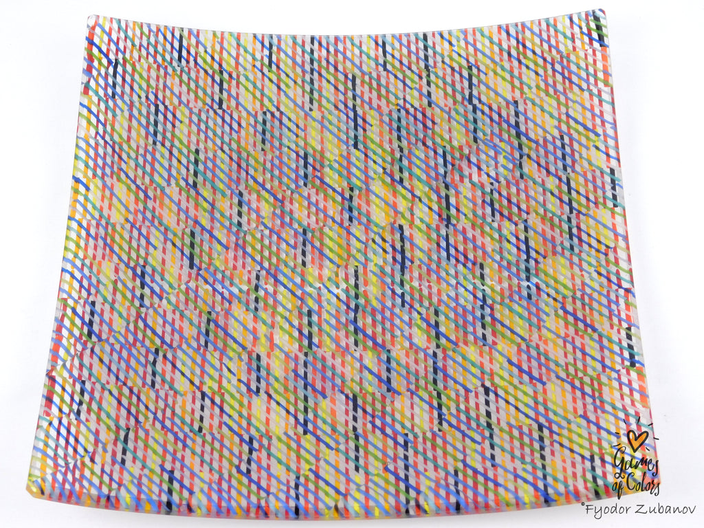 A square glass plate imitating fabric with a vibrant, multicolored geometric pattern featuring diagonal stripes and mesh-like textures in pink, yellow, blue, green.