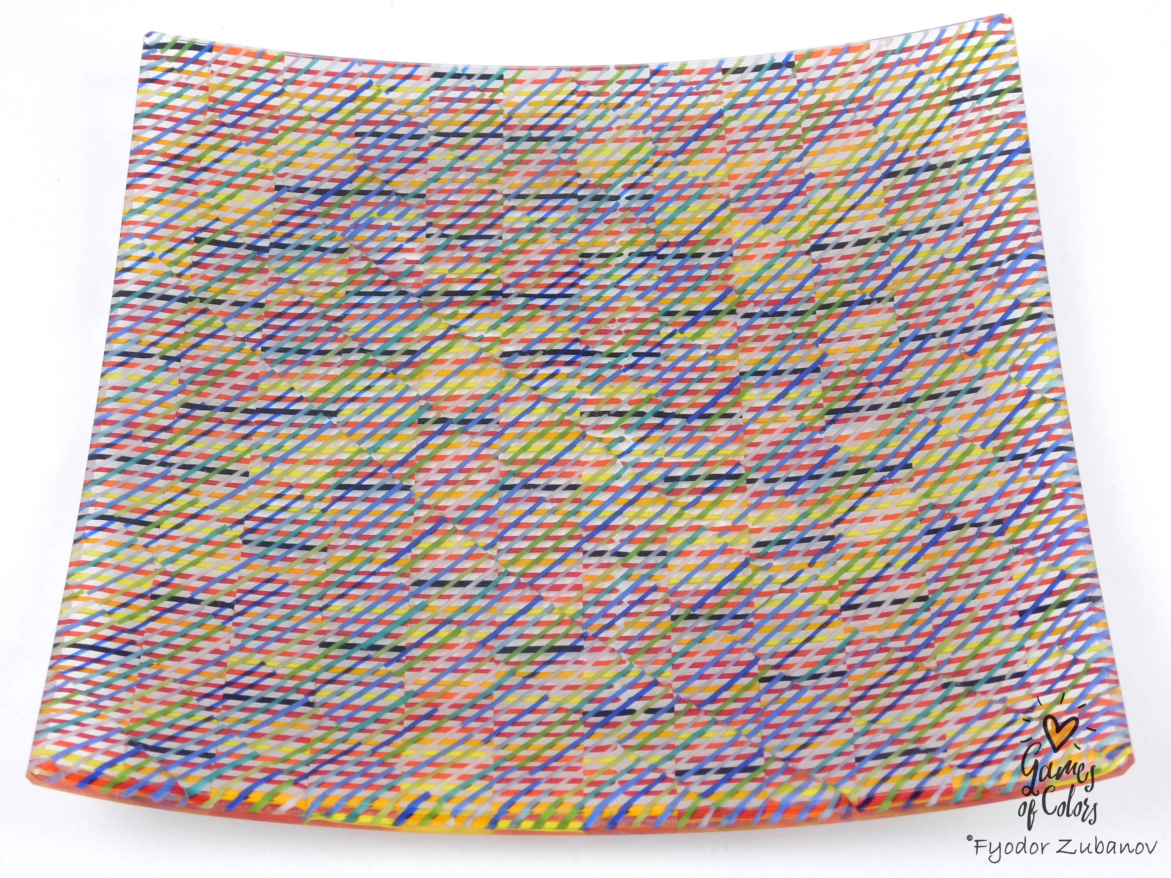 A square glass plate imitating fabric with a vibrant, multicolored geometric pattern featuring diagonal stripes and mesh-like textures in yellow, blue, green. and a watermark in the bottom right corner reads 'Fyodor Zubanov' and 'Games of Colors'.
