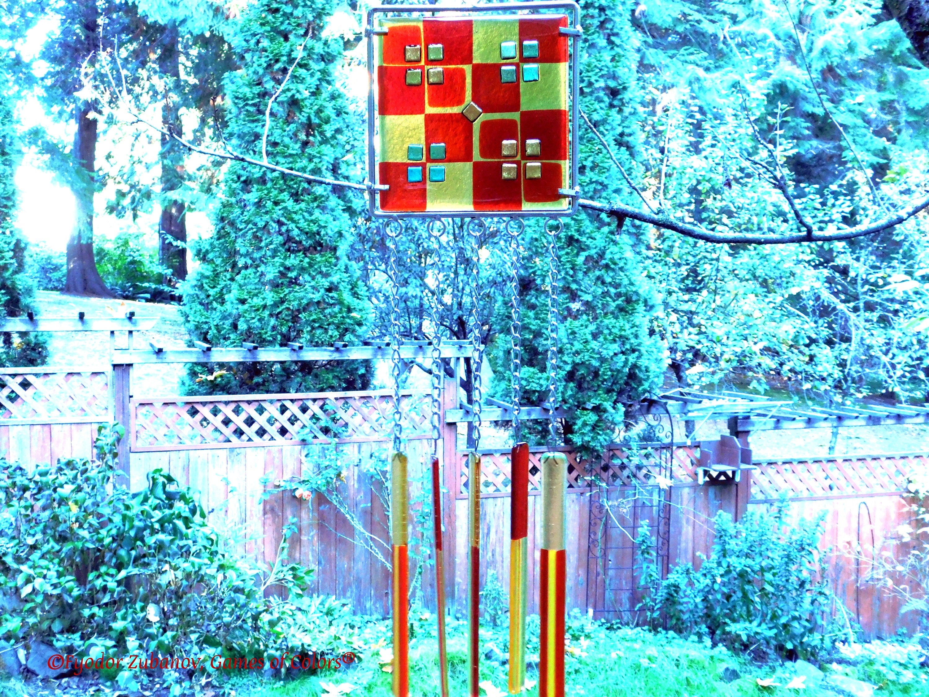 Wind chime with the main glass body surrounded by black frame and glass strips hanging on short chains