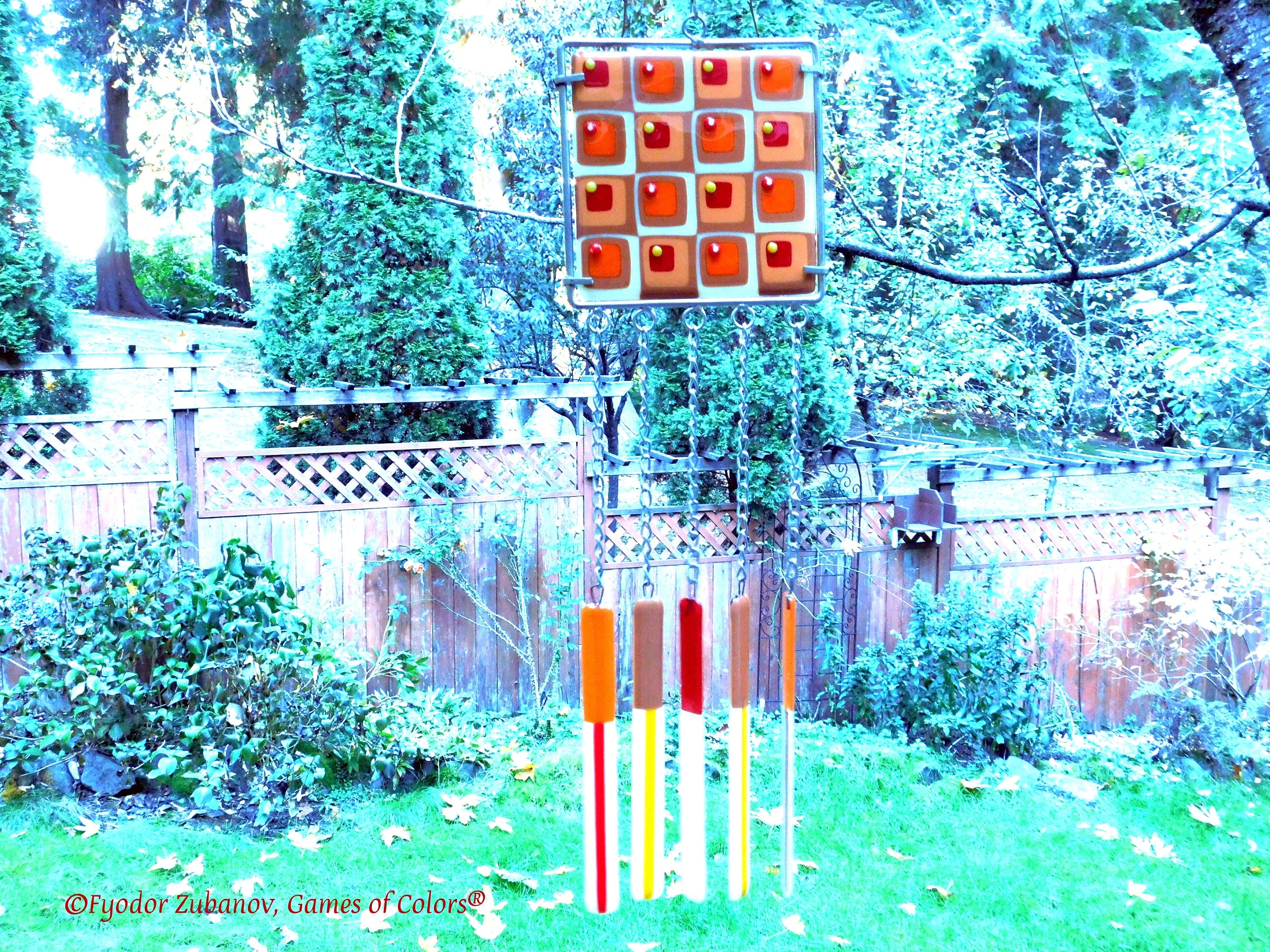 Wind chime with the main glass body surrounded by black frame and glass strips hanging on short chains